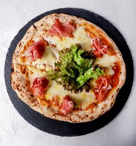 Pizza de jamón serrano con masa crujiente y sabor único.