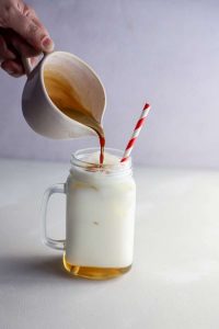 Ice Latte de Bonafide servido en un vaso transparente con hielo, leche y un shot de café molido, decorado con syrup de caramelo.